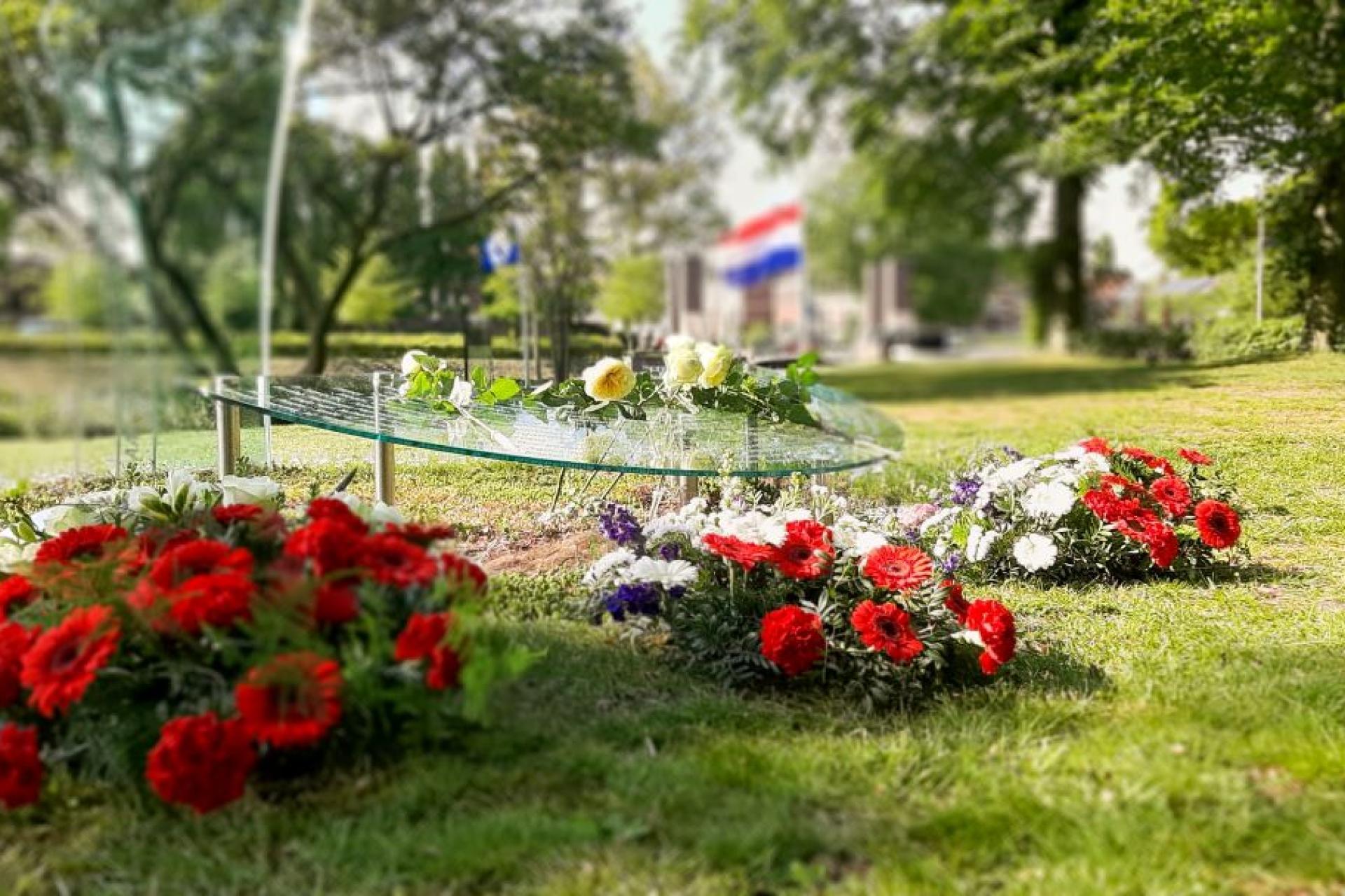 Rode bloemen op begraafplaats met Nederlandse vlag